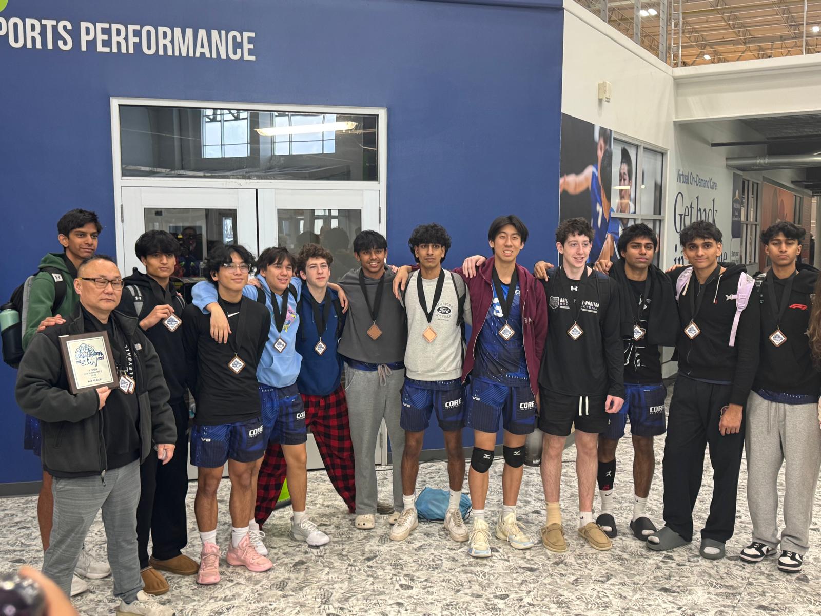 The team and their coach lined up in a concourse showing medals and a tournament bracket plaque